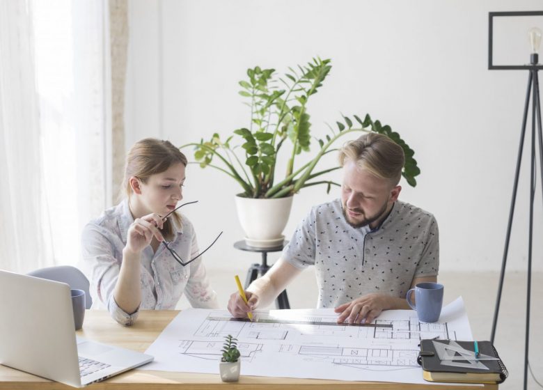 pretty-woman-looking-blueprint-while-her-colleague-working-it